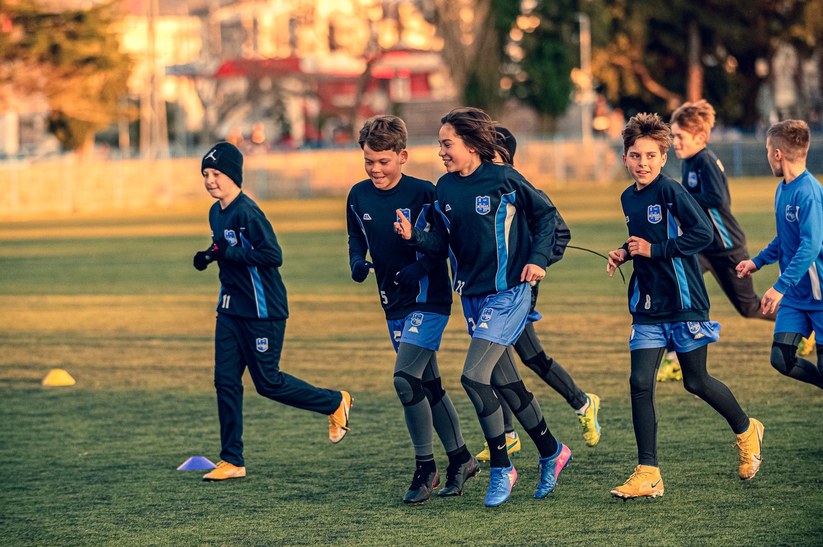 Young footballers in club kit jogging together in a warm-up
